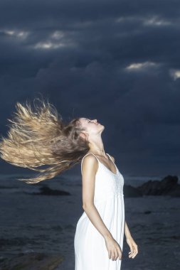 woman moving her hair on the beach at sunset