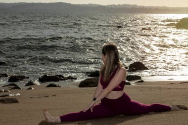 pretty flexible blonde woman doing stretching on the beach