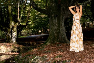 Kahverengi saçlı, yaz elbisesi giymiş bir kadınla Sakin Orman Cenneti