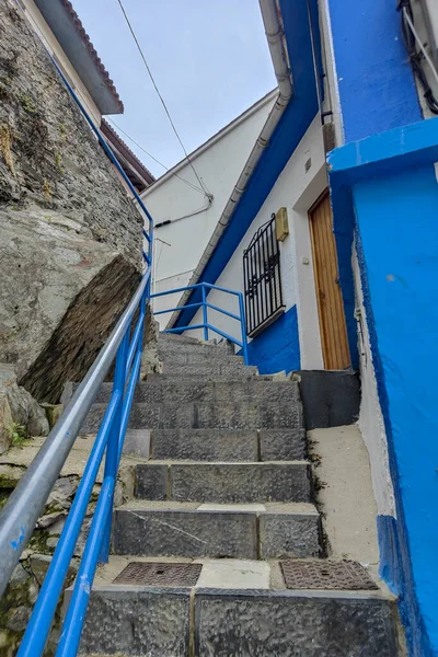 quaint staircase with blue railings leading to a charming white and blue house, under a clear sky