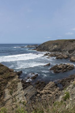 dinamik ama dinamik bir doğal güzellik kayalık bir sahil şeridinde dalgalar berrak bir gökyüzü altında çarpıyor.