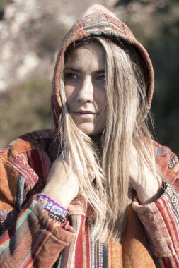 Renkli kapüşonlu sarışın kadın, açık havada bilezik takıyor, doğal bir geçmişi var.