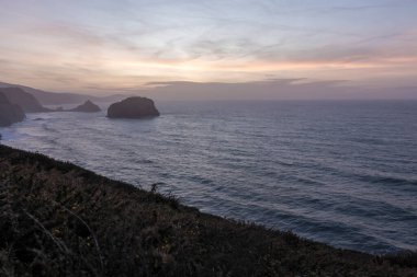 Okyanus üzerinde sakin bir günbatımı, gökyüzü ve denizdeki renklerin etkileşimiyle güçlenen bir sakinlik ve güzellik hissi sunuyor.