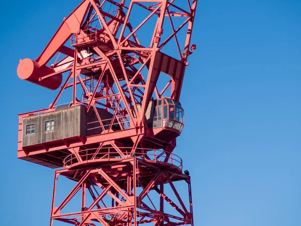 red crane against a clear blue sky, highlighting industrial design and engineering against nature's backdrop
