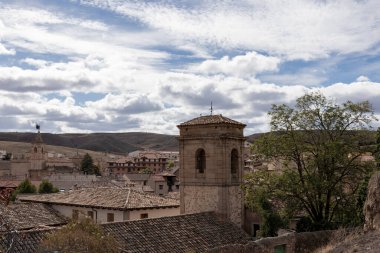 Kulesi ve eski binaları olan tarihi bir kasaba. Kabarık bulutlar ve doğa zeminine karşı kurulmuş.