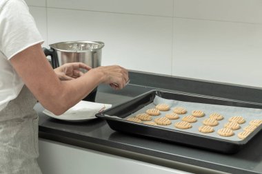 Kişi kurabiye hamurunu pişirmeye hazır bir tepsiye koyar.