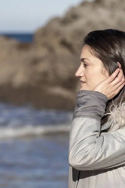 stock image Woman in Winter Coat Admiring the Ocean by Rocky Shoreline