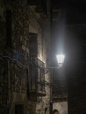 Geceleyin tek bir sokak lambasıyla aydınlatılmış eski bir taş bina.