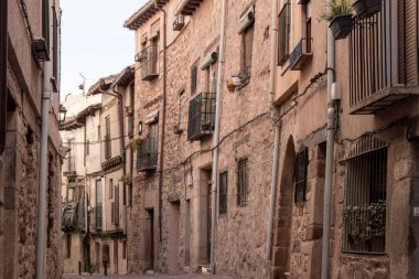 Büyüleyici bir İspanyol köyünde, taştan binaları ve balkonları olan dar bir kaldırım taşı caddesi.