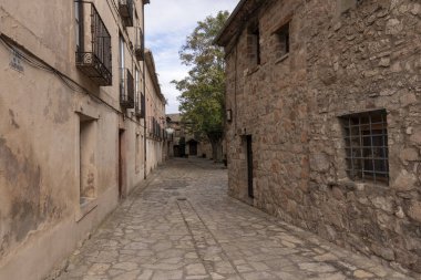Tarihi bir köyde dar bir kaldırım taşı caddesi, kırsal taşlarla çevrili ve balkonlu alçı binalar ve barışçıl bir atmosfer..