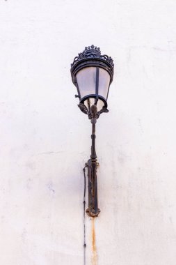 Bir sokak lambası duvara asılıyor. Lamba eski ve altın kaplama. Işık söndü ve lamba yanmadı.