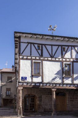 Üzerinde mavi işaret olan beyaz bir bina. Tabelada 