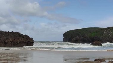 Okyanus kayalara çarpıyor, güçlü ve dramatik bir sahne yaratıyor.