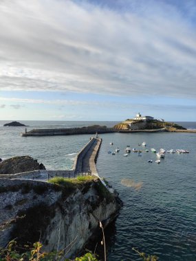 Tapia Adası, deniz feneriyle Tapia de Casariego kasabasının limanındaki kayıkları koruyor. İspanya, Asterias 'ta, bulutlu bir gökyüzünün altında.