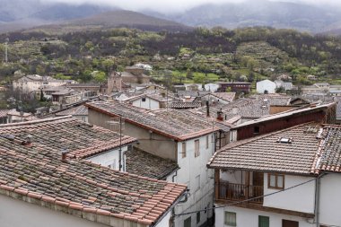 Geleneksel kil kil kiremit çatılar bulutlu bir gökyüzünün altındaki pitoresk bir dağ köyünde evleri kaplıyor ve büyüleyici bir kırsal manzara yaratıyor.