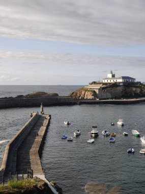 Bulutlu bir günde Tapia de Casariego, Asterias, İspanya 'da adacığa çıkan beton iskelenin yanında yüzen botlar