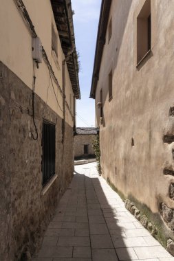 Resimli bir İtalyan köyünde yıpranmış binalar arasında boş asfalt bir ara sokak büyüleyici ve zamansız bir sahne yaratıyor.