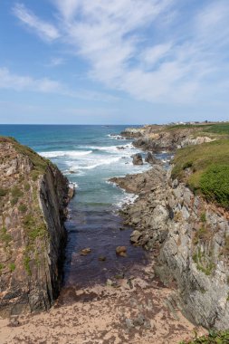 Güçlü okyanus dalgalarının nefes kesici manzarası kayalık kıyı şeridini vuruyor, kumlu bir kumsalla sakin bir koy oluşturuyor, doğanın ham güzelliğinin tadını çıkarmak için mükemmel bir yer.