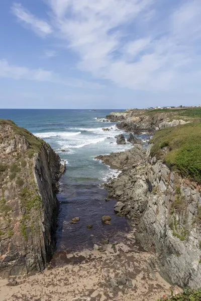 Güçlü okyanus dalgalarının nefes kesici manzarası kayalık kıyı şeridini vuruyor, kumlu bir kumsalla sakin bir koy oluşturuyor, doğanın ham güzelliğinin tadını çıkarmak için mükemmel bir yer.