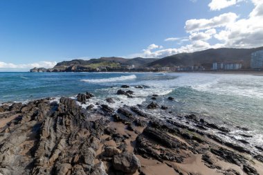 Okyanus dalgaları güneşli bir günde Bakio, Bask bölgesindeki kayalara çarpıyor.