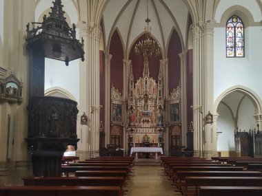 Boş sıraları, vitray penceresi ve avizesi olan Katolik bir kilisede ahşap minber ve sunak süsleyin.