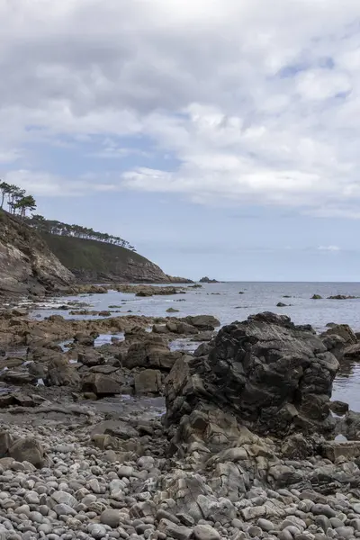 Rocky plajı bulutlu gökyüzünün altındaki yeşil uçuruma çıkıyor.