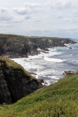 İngiltere, Cornwall 'daki kayalık sahile çarpan engebeli kayalıkların ve güçlü dalgaların manzarası dramatik bir kıyı manzarası yaratıyor.