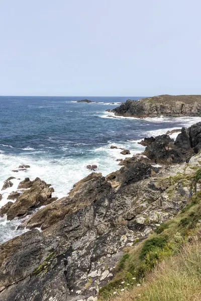 Güçlü okyanus dalgalarının bulutlu bir gökyüzünün altında engebeli, kayalık bir kıyı şeridine çarpması nefes kesici bir manzara.