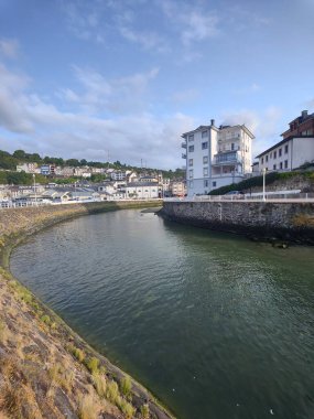 Serene nehri berrak mavi gökyüzünün altında büyüleyici bir kıyı kasabasında kıvranıyor, huzurlu ve manzaralı bir manzara sunuyor.