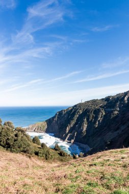 Güçlü dalgaların nefes kesici manzarası Cabo Belediye Başkanı deniz feneri yakınlarındaki açık mavi gökyüzünün altında kayalıklara çarpıyor.