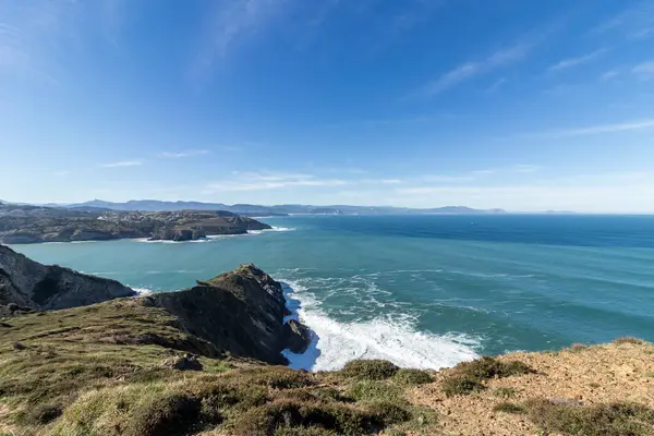 Kayalık bir kıyı şeridinin nefes kesen manzarası dingin mavi gökyüzünün altında engin okyanusla birleşerek pitoresk bir manzara yaratıyor.
