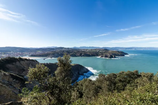 Güneşli bir günde, önünde deniz çamı olan bir uçurumdan Cantabrian Denizi manzarası