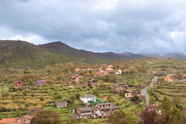 İspanya kırsalının cazibesini gösteren manzara tepelere dağılmış evler, bulutlu bir gökyüzünün altında.