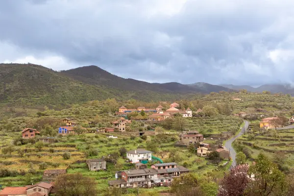 İspanya kırsalının cazibesini gösteren manzara tepelere dağılmış evler, bulutlu bir gökyüzünün altında.