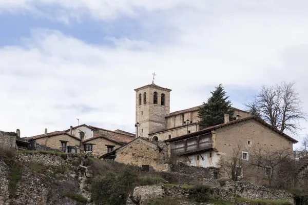 Tanınmış taştan bir kilise ve geleneksel evlerin yer aldığı tarihi bir İspanyol köyünün huzurlu manzarası, zamansız bir cazibe hissi uyandırıyor.