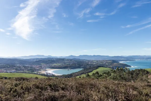 Sersemletici panoramik manzara, pitoresk bir körfez, yeşil tepeler, ve uzak dağlar Kuzey İspanya 'da açık mavi bir gökyüzü altında