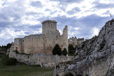 Ispanya 'daki rello kalesinin harabelerinin manzarası, kısmen yıkılmış duvarları ve kuleleri, bulutlu bir gökyüzünün altındaki yeşil vadiye bakan bir tepenin üzerinde duruyor.
