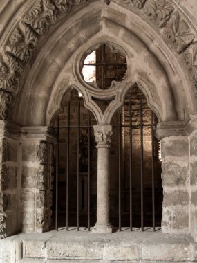 Süslü bir taş kemerin arkasındaki dini bir heykeli koruyan metal parmaklıklar antik bir bina içinde saygı ve güvenlik manzarası yaratıyor.