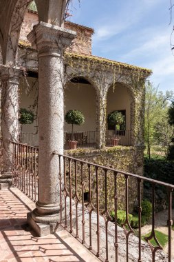 İspanyol bir binada sarmaşık kaplı kemer ve sütunlarla pitoresk bir avluyu aydınlatan güneş ışığı