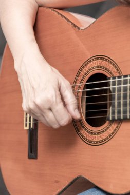 Müzisyenlerin ellerinin akustik gitar çalıp enstrümanın karmaşık ayrıntılarına ve müzisyenin yeteneğine odaklandığı yakın plan.
