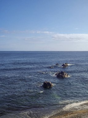 Cantabrian Denizi 'nin derin mavi sularından yükselen kayalık adaları içeren sersemletici deniz manzarası, Asterias, İspanya' da berrak mavi bir gökyüzünün altında,