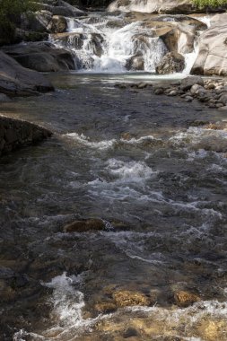 Granit kayaların üzerinden akan temiz dağ nehri yuste içinde küçük şelaleler oluşturuyor.