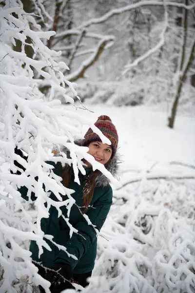 Žena Usmívá Když Vykoukne Zpoza Větví Ztěžklého Sněhem Zimním Lese Royalty Free Stock Fotografie
