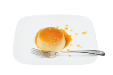 Karamel soslu panna cotta ve beyaz tabaktaki çatal.