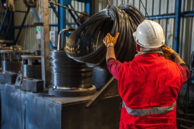 Metal endüstrisinde demir ya da çelik tellerden bobinler tutan işçi ya da adam. İnşaat endüstrisi çelik fabrikası imajı