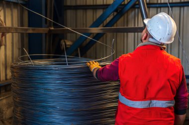 Metal endüstrisinde demir ya da çelik tellerden bobinler tutan işçi ya da adam. İnşaat endüstrisi çelik fabrikası imajı