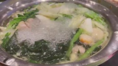 Sukiyaki ya da shabu yapmak için sıcak bir tencerede yemek pişirmek.