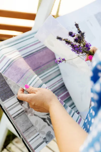 Woman choosing fabric for new curtains. Girl holds a bouquet of lavender in her hands. Fragrant lavender flowers