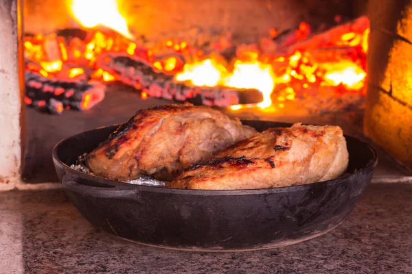 鋳鉄製のフライパンで焼いた肉は 薪オーブンの前に立っています 薪オーブンで火で肉を調理するためのレシピ 写真シリーズ — ストック写真