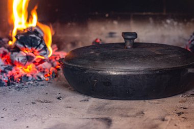 Ahşap fırına demir tava atın. Yanan bir ateşin yanında kızartma tavası. Yemek pişirme süreci. Fotoğraf serisi